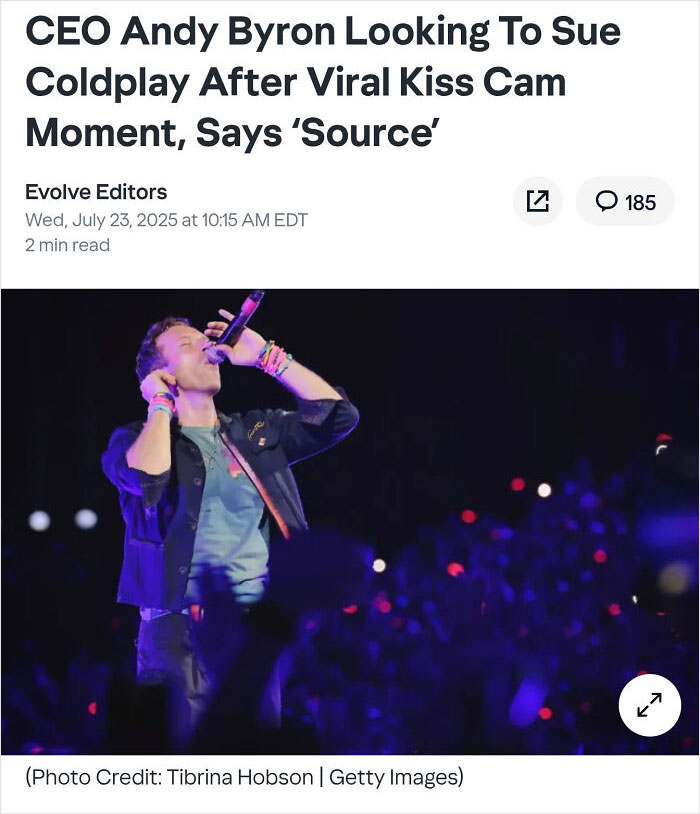 Singer performing on stage with microphone in hand during a live concert in front of a large audience.