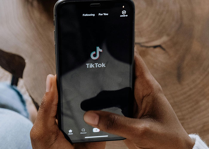 Person holding a smartphone with TikTok app open, illustrating jobs that only a person without a soul would do.