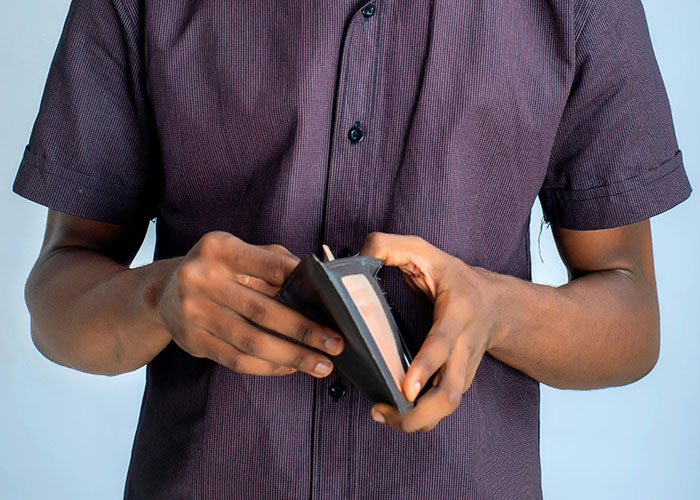 Man in a purple shirt holding an open wallet showing money, illustrating wild and embarrassing drinking stories.