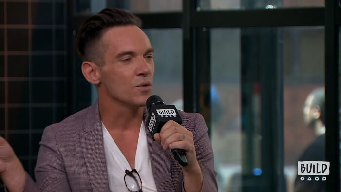 Man speaking into a microphone during an interview, discussing celebrities Hollywood tried to make leading A-listers.