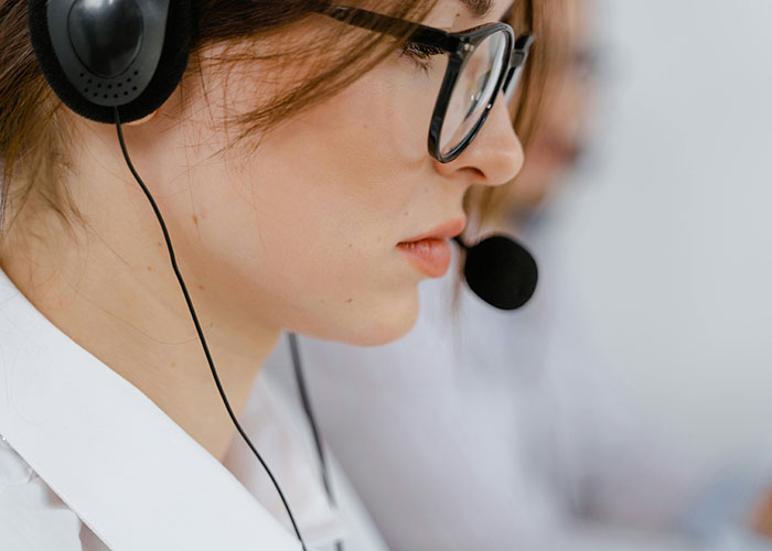 Close-up of a woman with glasses wearing a headset working in a call center, symbolizing jobs only a person without a soul would do.