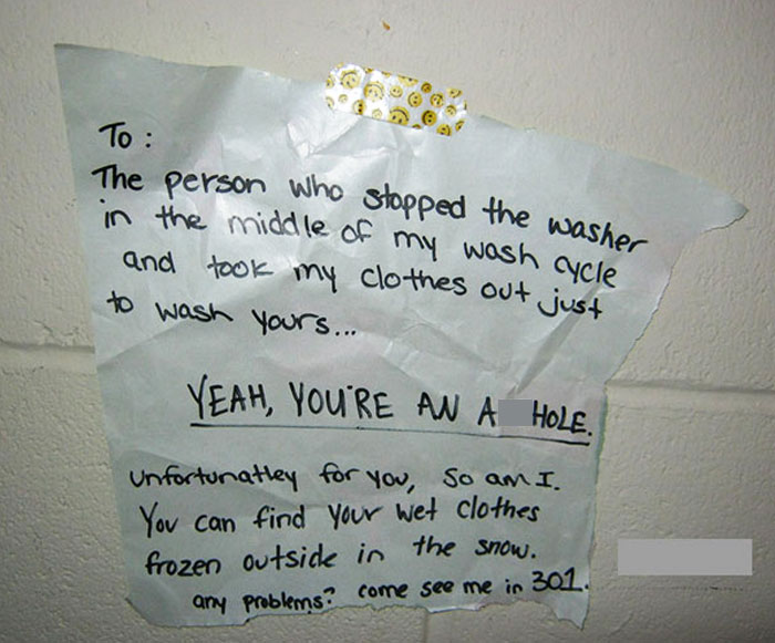 Handwritten angry neighbor note about laundry theft taped to a wall, showcasing unhinged neighbors' notes humor and conflict.