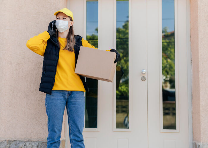 Woman wearing a mask and yellow cap holding a box, talking on phone, illustrating chilling true stories about scary sounds at night.