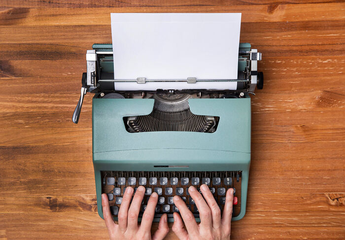 Hands typing on a vintage typewriter on a wooden desk, symbolizing creativity and confidence of school kids' wild feats.