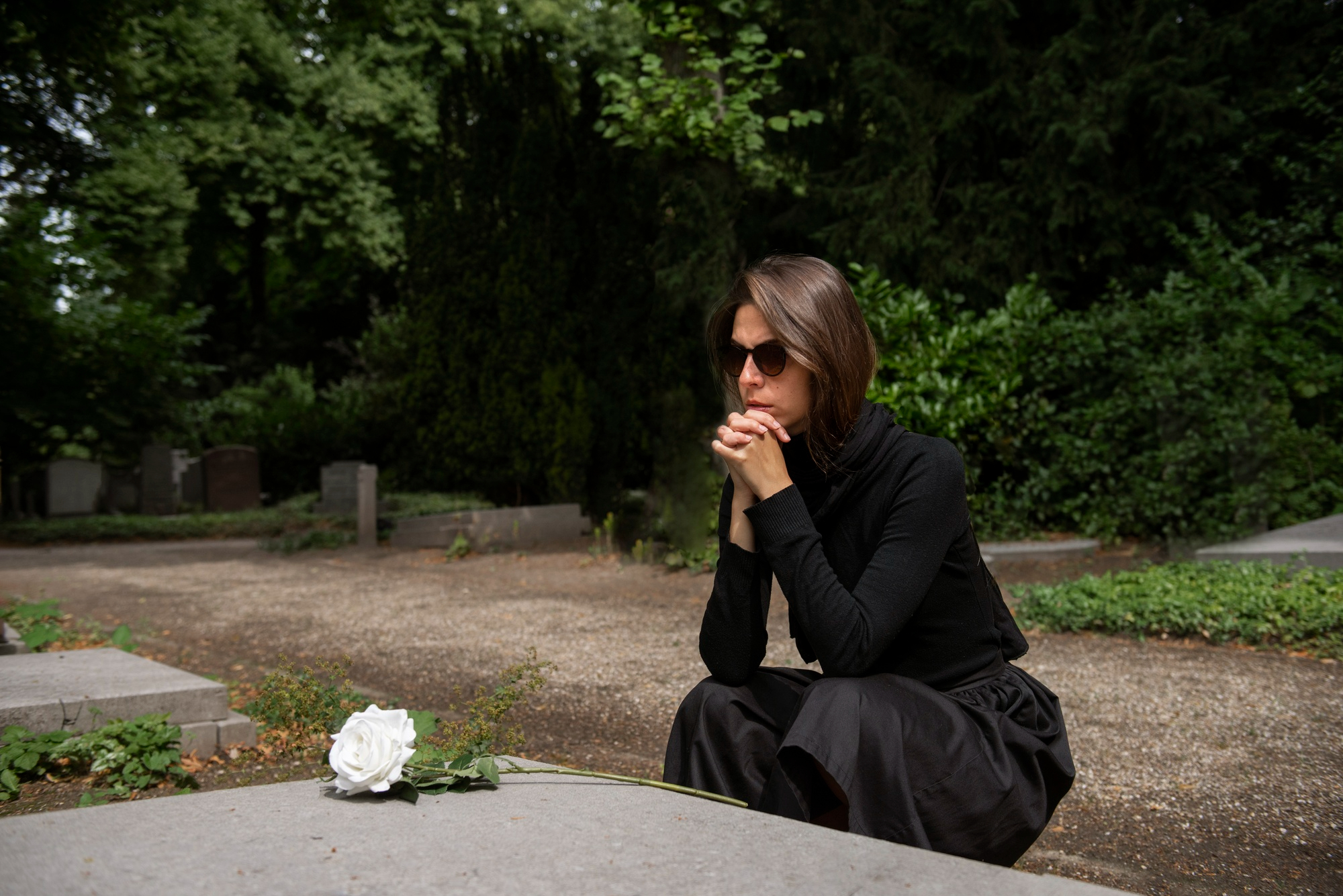 Woman in black mourning attire at a gravesite, reflecting on widow and stepkids feeling hurt and abandoned.