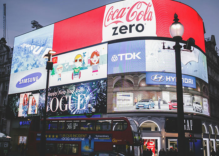 Cityscape with digital billboards displaying various brand ads, highlighting jobs that only a person without a soul would do.