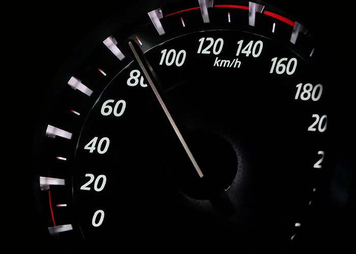 Close-up of a speedometer showing a vehicle driving over the speed limit around 110 km/h at night.