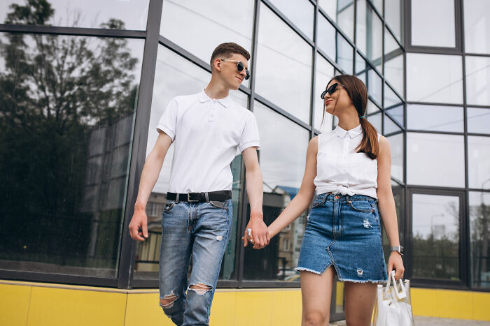 Young couple wearing sunglasses holding hands outdoors, representing smooth pickup lines and romantic connection.
