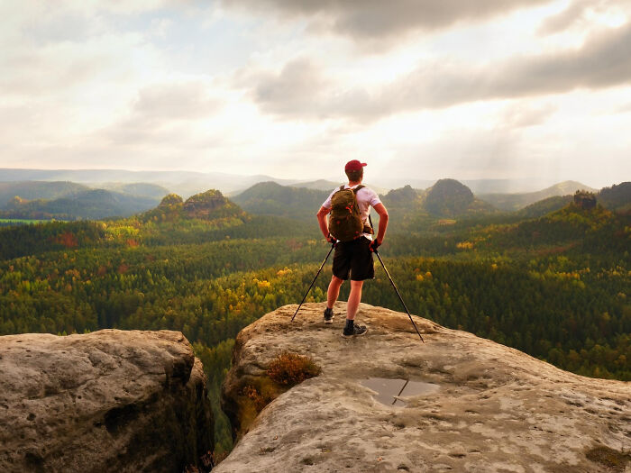 Person standing with hiking poles overlooking scenic mountain landscape, reflecting on moments they can't brag about online.