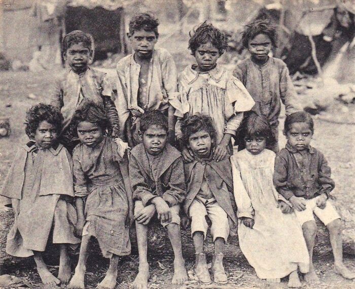 Group of Indigenous Australian children from the 1900s in traditional and early Western clothing, captured in a rare historic photo