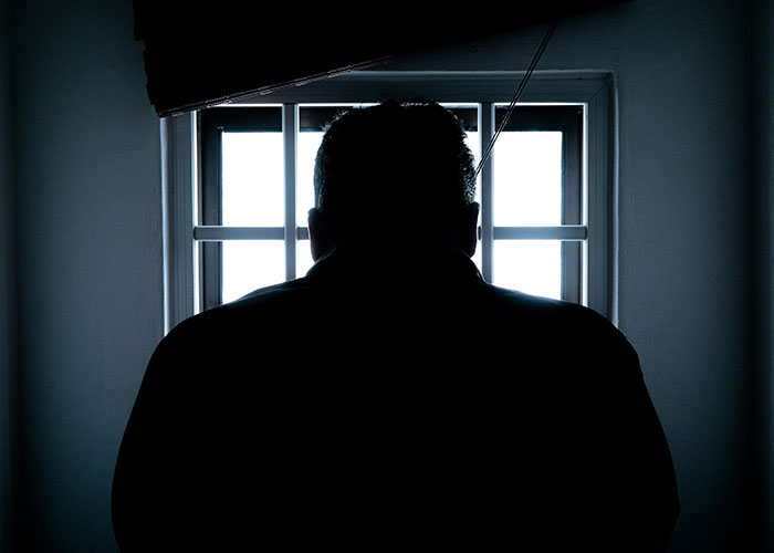 Silhouette of a person looking out a window with bars, symbolizing jobs that only a person without a soul would do.