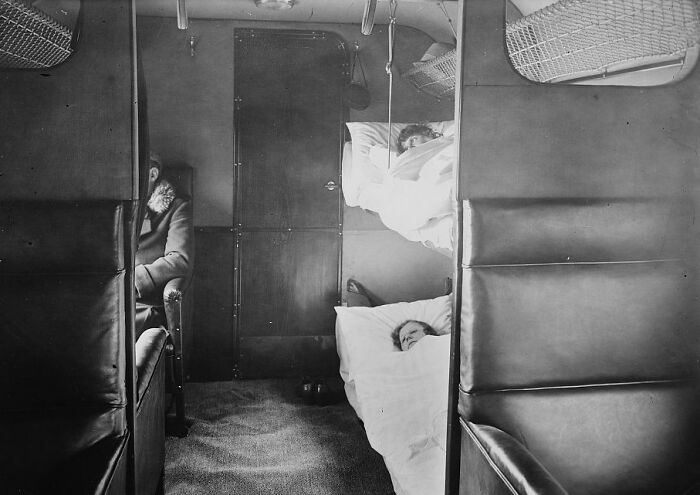 Vintage black and white photo showing passengers resting in private sleeping compartments, capturing flying glamour era.