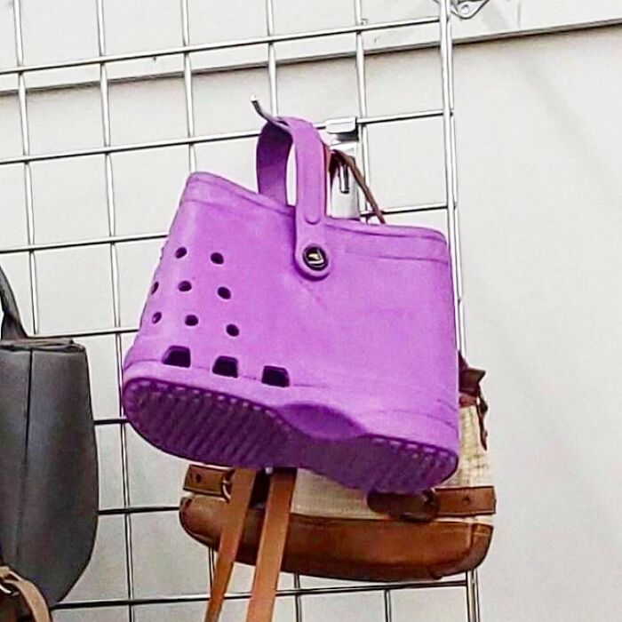 Purple handbag shaped like a Crocs shoe displayed among other bags, showcasing bizarre thrift store finds.