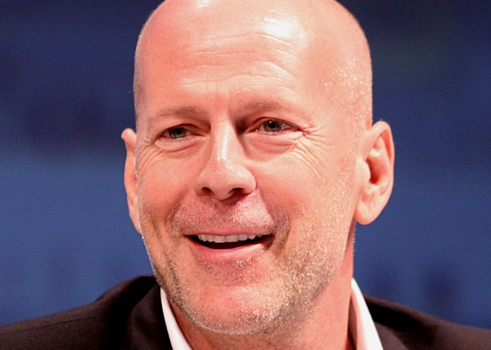 Smiling bald man in a suit jacket and white shirt, representing a total gentleman in celebrity encounters.