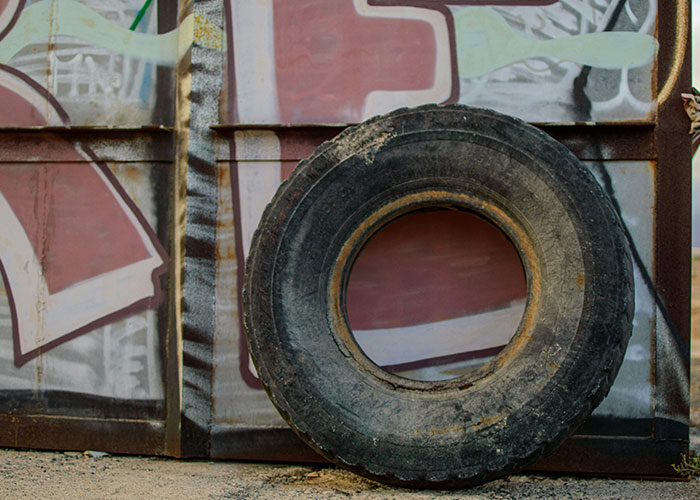 Old dirty tire leaning against a graffiti-covered wall illustrating wild and embarrassing drinking stories.