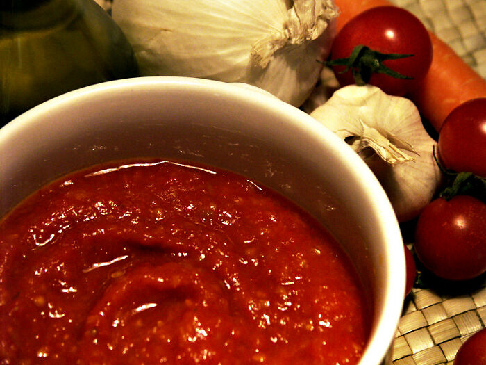 Bowl of tomato sauce with fresh tomatoes, garlic, and onions, representing restaurant workers facing unusual orders.