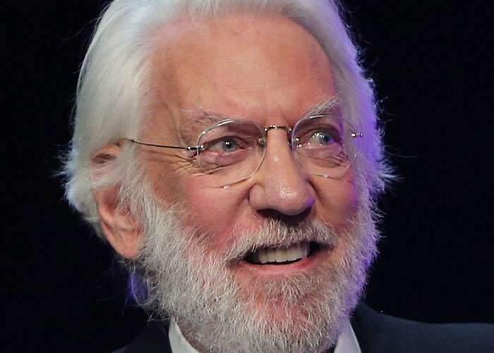 Elderly man with white hair and beard wearing glasses smiling, capturing a total gentleman celebrity encounter moment.