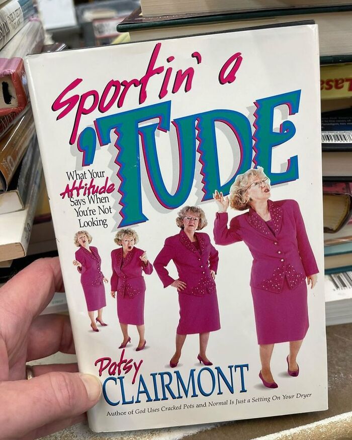 Hand holding a quirky book cover featuring multiple images of a woman in a magenta suit, found at a thrift store.