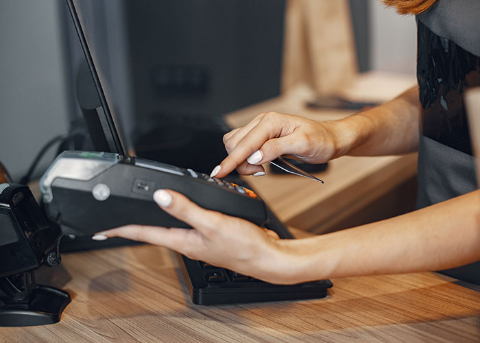 Person using a payment terminal at a store counter, relating to parents leaving kid unattended in pet store charges.
