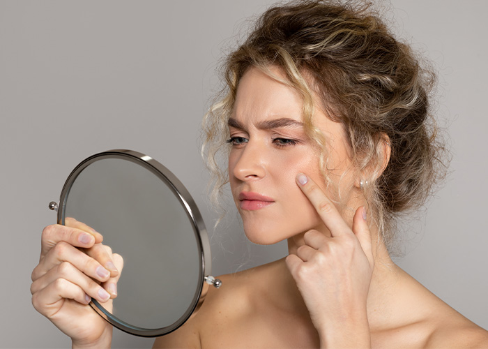 Woman examining skin closely in mirror, reflecting moments when rich people realized normal life differs for most people. - 11