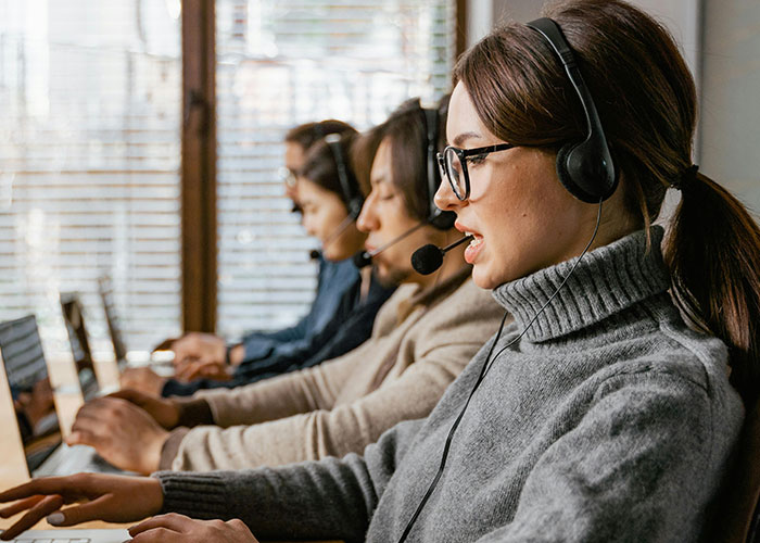 Call center workers with headsets focused on computers, illustrating challenging jobs without a soul involved.