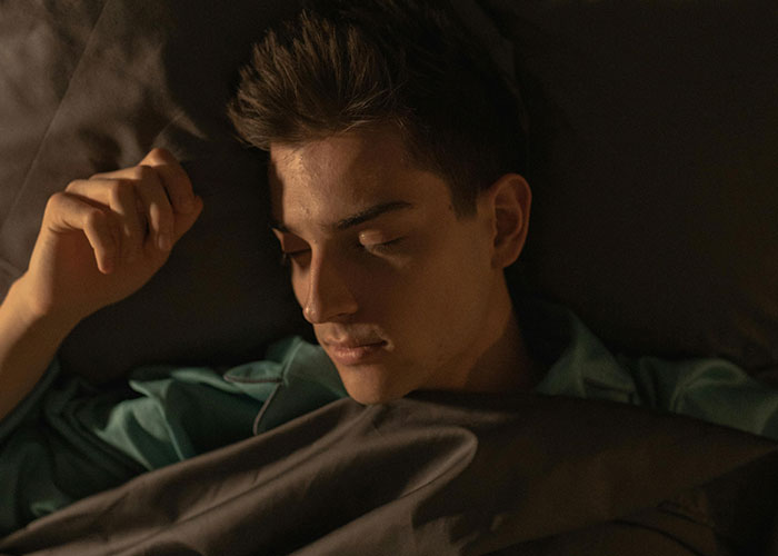 Young man sleeping in bed after a wild night, illustrating embarrassing drinking stories and poor alcohol decisions.