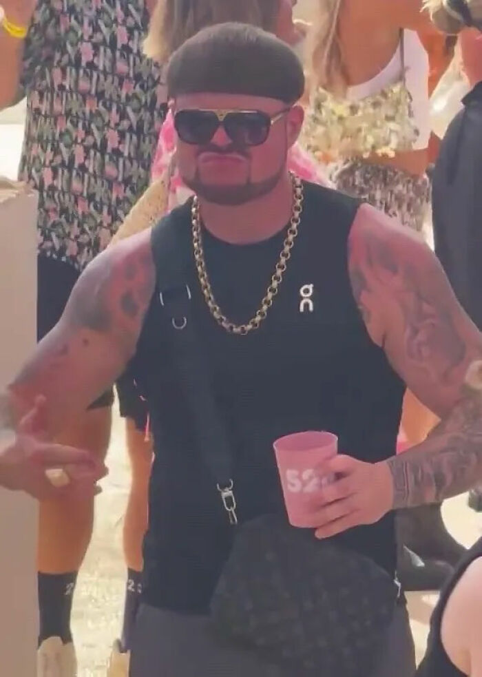 Man with unique haircut and tattoos wearing sunglasses and a gold chain at a crowded Ibiza event, Ibiza Final Boss style. Man with unique haircut and tattoos wearing sunglasses and a gold chain at a crowded Ibiza event, Ibiza Final Boss style.