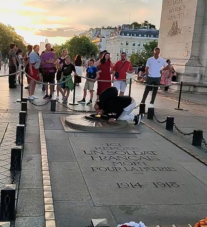 Man lighting cigarette on Tomb of Unknown Soldier while tourists watch, facing arrest and deportation controversy. - 3