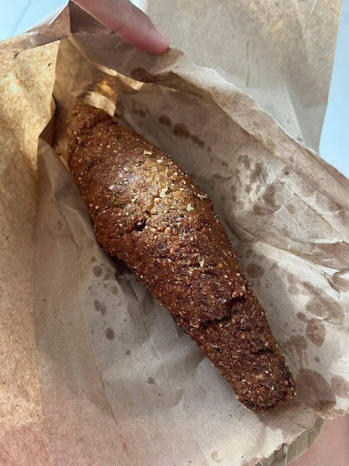Close-up of a brown, dense food item in a greasy paper bag, illustrating food nobody should eat for physical and mental health.