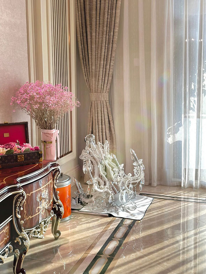 Broken expensive glass chandelier lying on floor near elegant furniture and sheer curtains in a bright room.