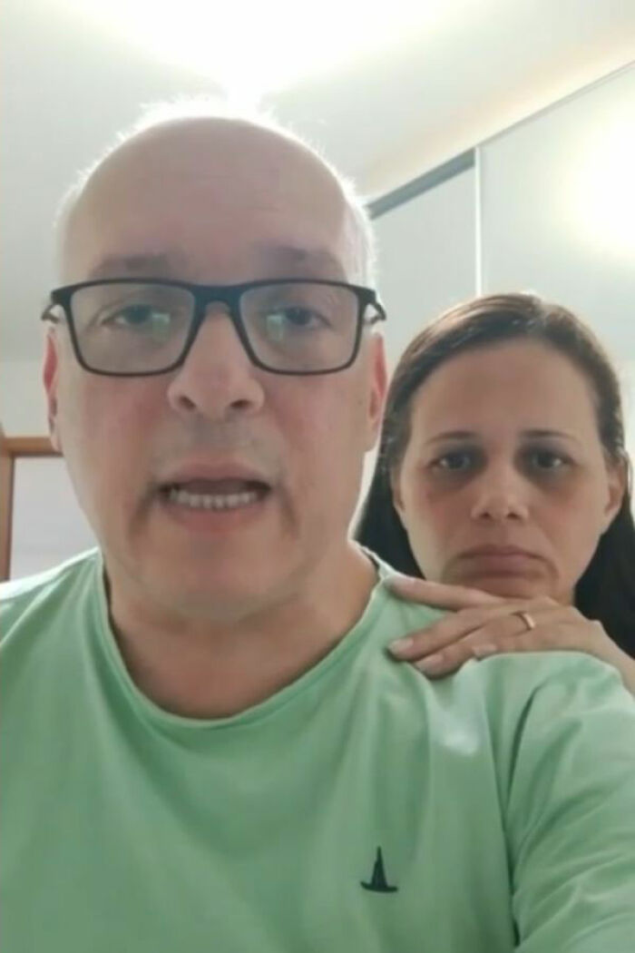 Middle-aged man with glasses and a woman behind him appearing serious, linked to pastor caught in thong and wig memes. Middle-aged man with glasses and a woman behind him appearing serious, linked to pastor caught in thong and wig memes.