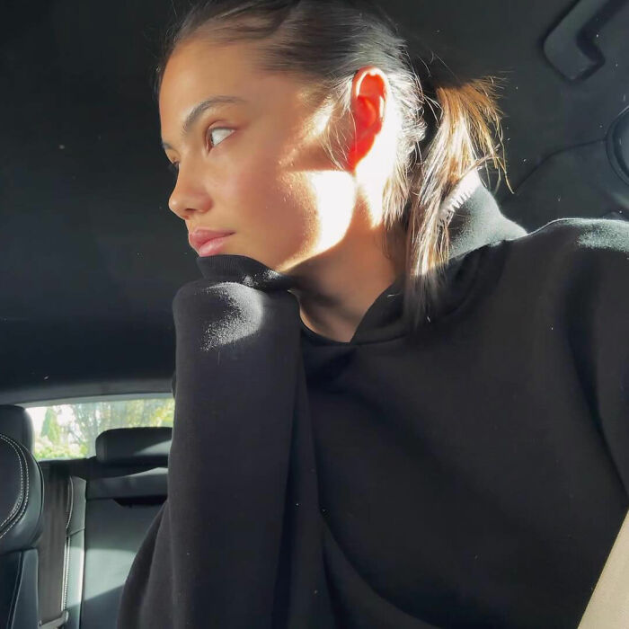 Tennis star looking thoughtful indoors with sunlight on face, reflecting on diva issues during match meltdown.