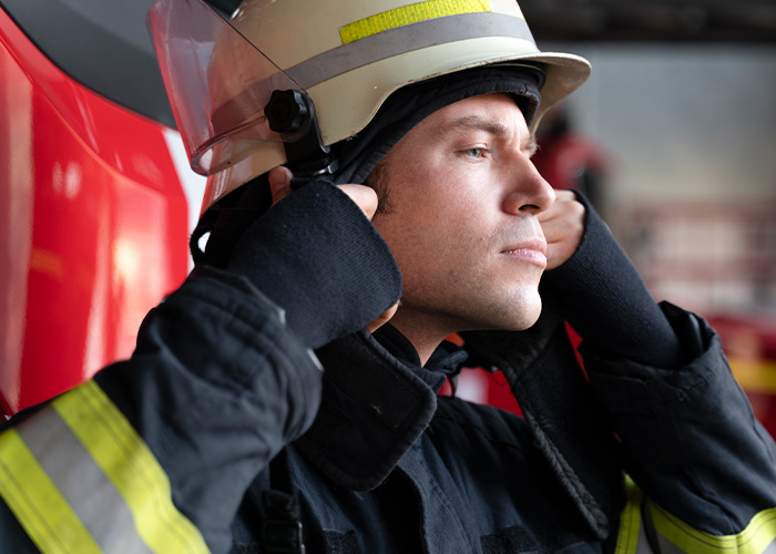 Firefighter wearing protective gear preparing to respond to a house fire caused by accidental fire hazards.