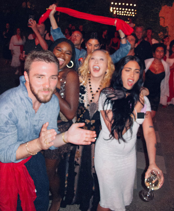 Group of people celebrating with Madonna's daughter Lourdes appearing to have a nip slip at her mom's birthday party.