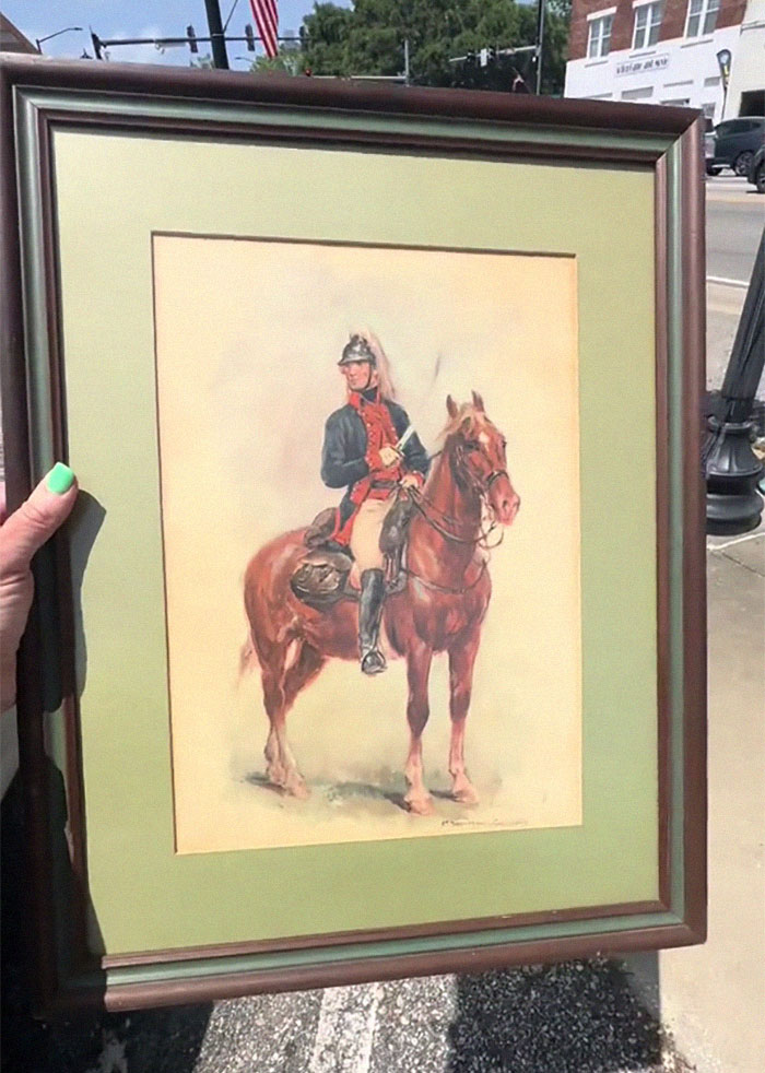 Woman holding framed painting of a soldier on horseback after discovering message on the back of the artwork outdoors. Woman holding framed painting of a soldier on horseback after discovering message on the back of the artwork outdoors.