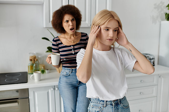 Woman expecting cousin to babysit looks upset as cousin refuses, causing tension in a modern kitchen setting.
