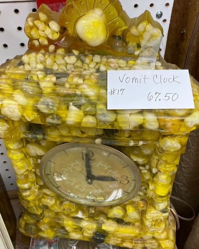 Bizarre thrift store clock covered in yellow and white objects with a sign reading Vomit Clock and price $67.50.