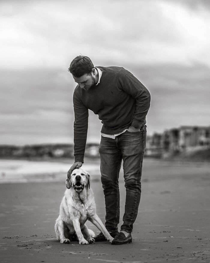 Man tenderly kissing his dog, capturing touching final moments between pets and their humans in black and white.