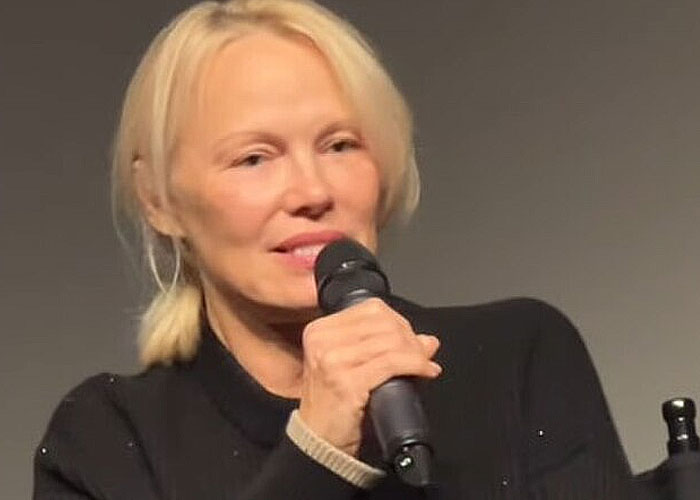 Woman with blonde hair speaking into microphone during a celebrity encounter sharing wild experiences at an event.