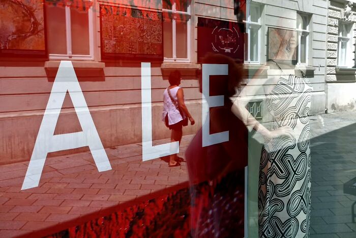 Street scene reflected in a shop window with a mannequin and a pedestrian, capturing life’s unseen, unposed moments on the streets.