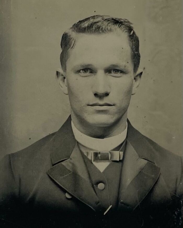 Victorian man in formal attire with bow tie, showcasing classic handsome features in a vintage black and white portrait.