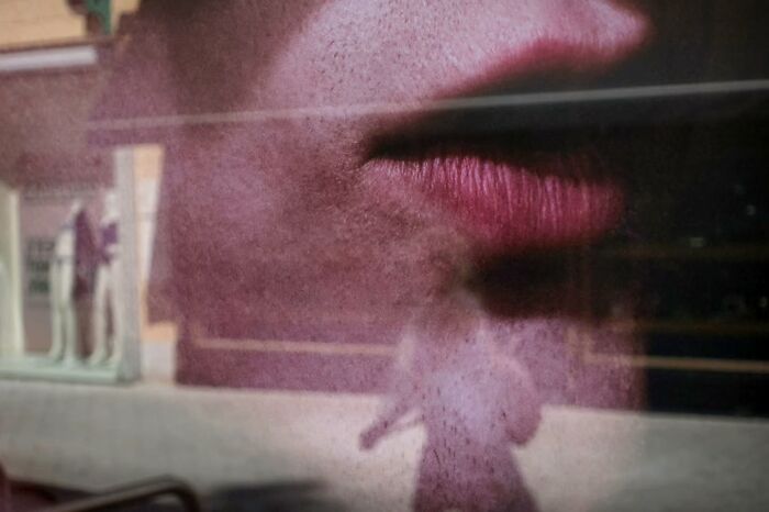 Blurred street scene with shadow of a person and a large close-up of lips, capturing unseen unposed moments.