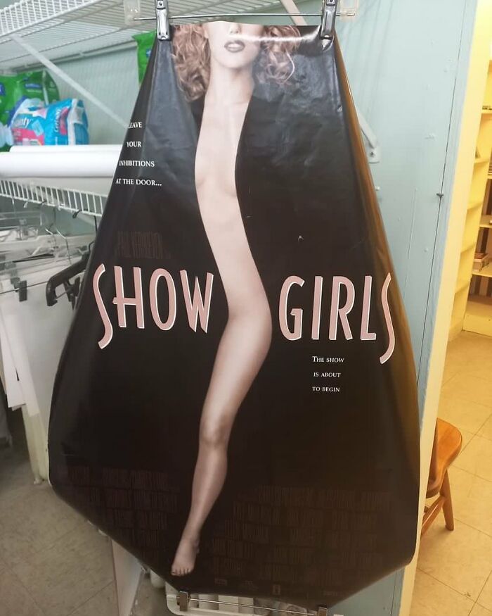 Bizarre thrift store find of a distorted Show Girls movie poster hanging in a closet with cleaning supplies nearby.