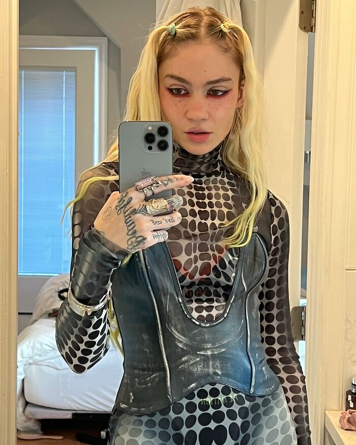 Celebrity taking a mirror selfie wearing a patterned outfit and rings, showcasing how out-of-touch celebs can be when trying to be relatable.