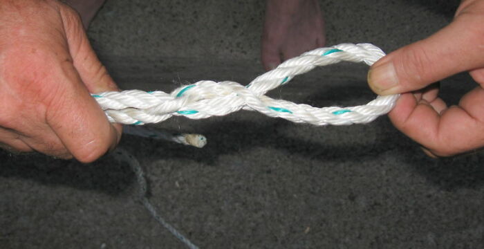 Two hands tying a white rope against a dark background, illustrating unexpected discoveries by snooping parents.