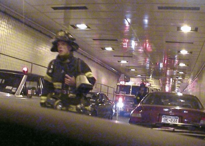 Firefighter in a tunnel with emergency vehicles and cars, part of unsettling images from morbid knowledge online group.