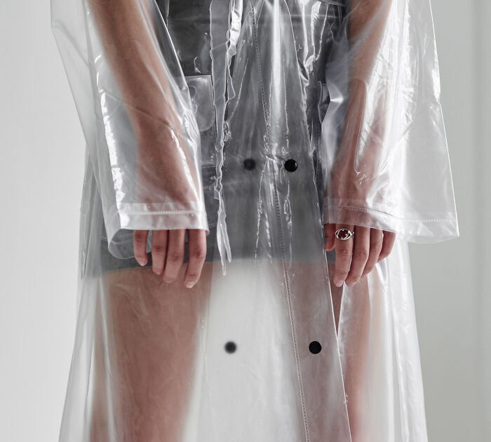 Close-up of school kid wearing a clear plastic raincoat, showcasing confidence and unique style with bold fashion choice.