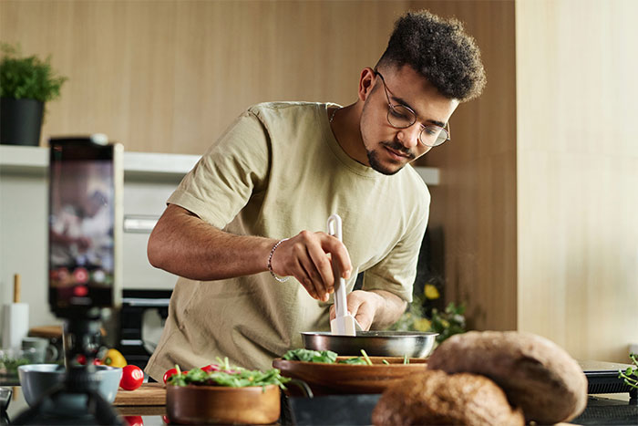Man concentrating while preparing dinner in kitchen, illustrating cooking before woman threw away dinner he made.