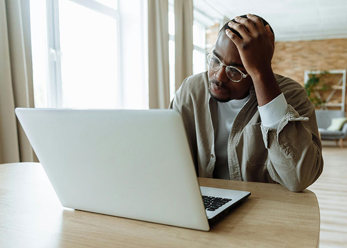 Man looking sick and stressed while working on laptop, wondering if dad touching his food is intentional.