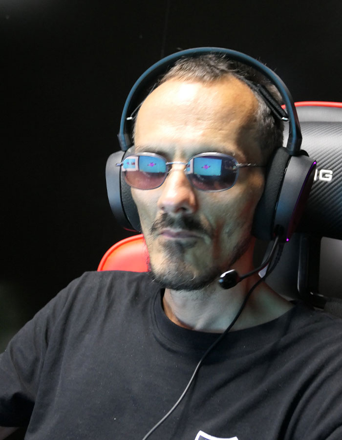 Streamer wearing sunglasses and headset sitting in a gaming chair during a live broadcast session. Streamer wearing sunglasses and headset sitting in a gaming chair during a live broadcast session.